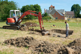 An excavator takes off the topsoil